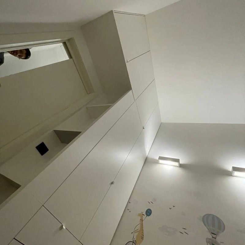 Ripiano ricavato da piano IKEA utilizzato come finitura tra armadio e parete per ottimizzare lo spazio.